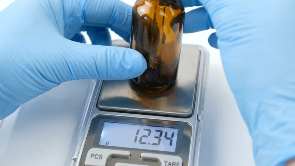 Measuring fragrance oil on a digital scale, part of a home perfume business cost